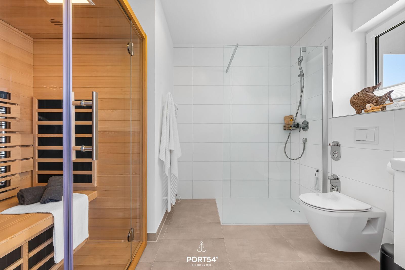 Dusche, Toilette und Sauna in einem Raum.