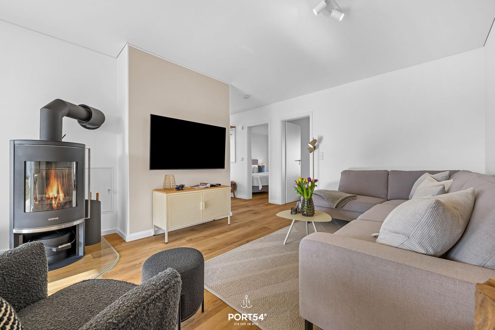 Wohnzimmer mit Kamin, Sofa und Fernseher. Holzboden und moderne Einrichtung.