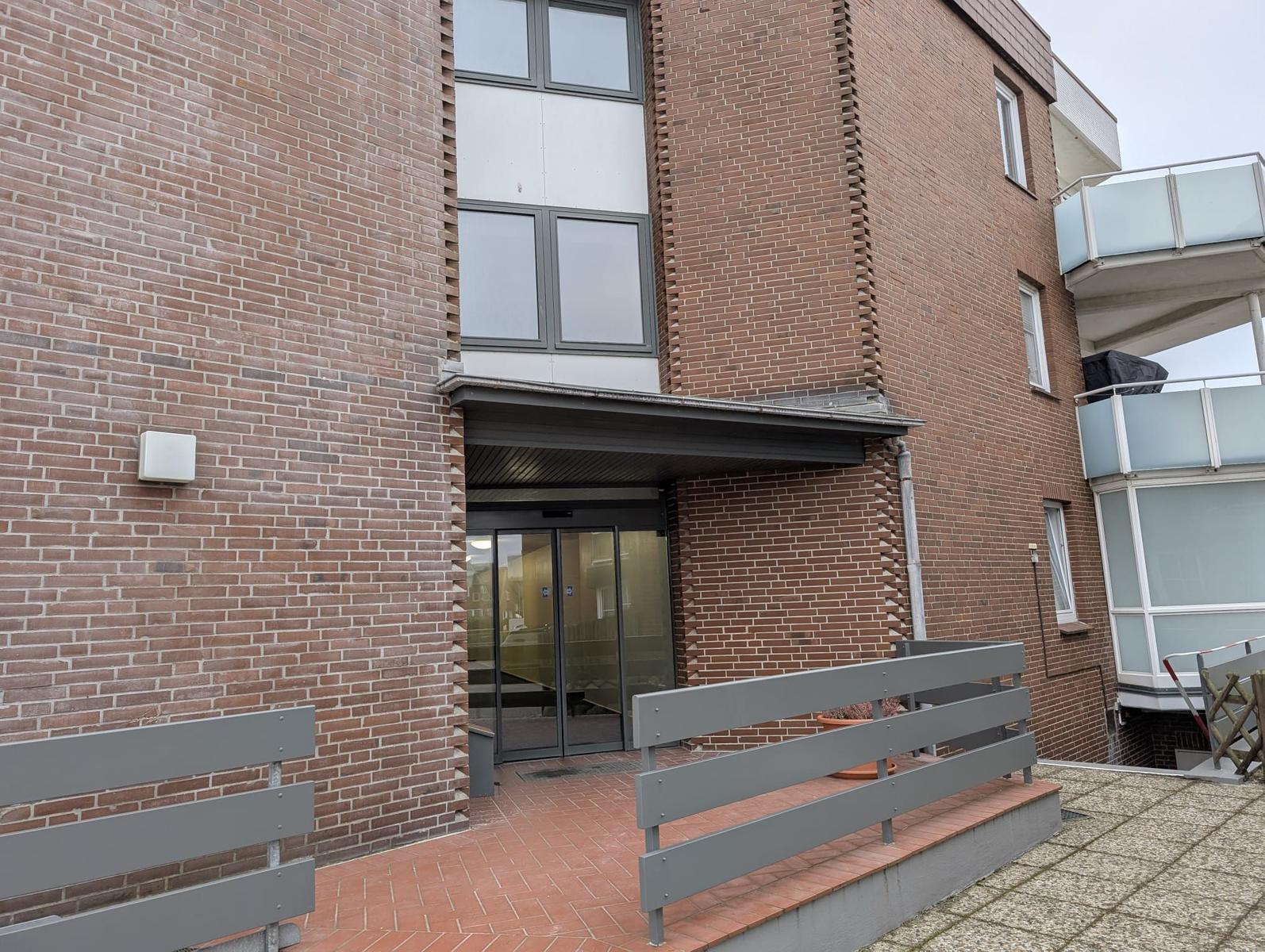 Eingangsbereich mit Glas-Tür und Brüstung. Gebäude aus Backstein.