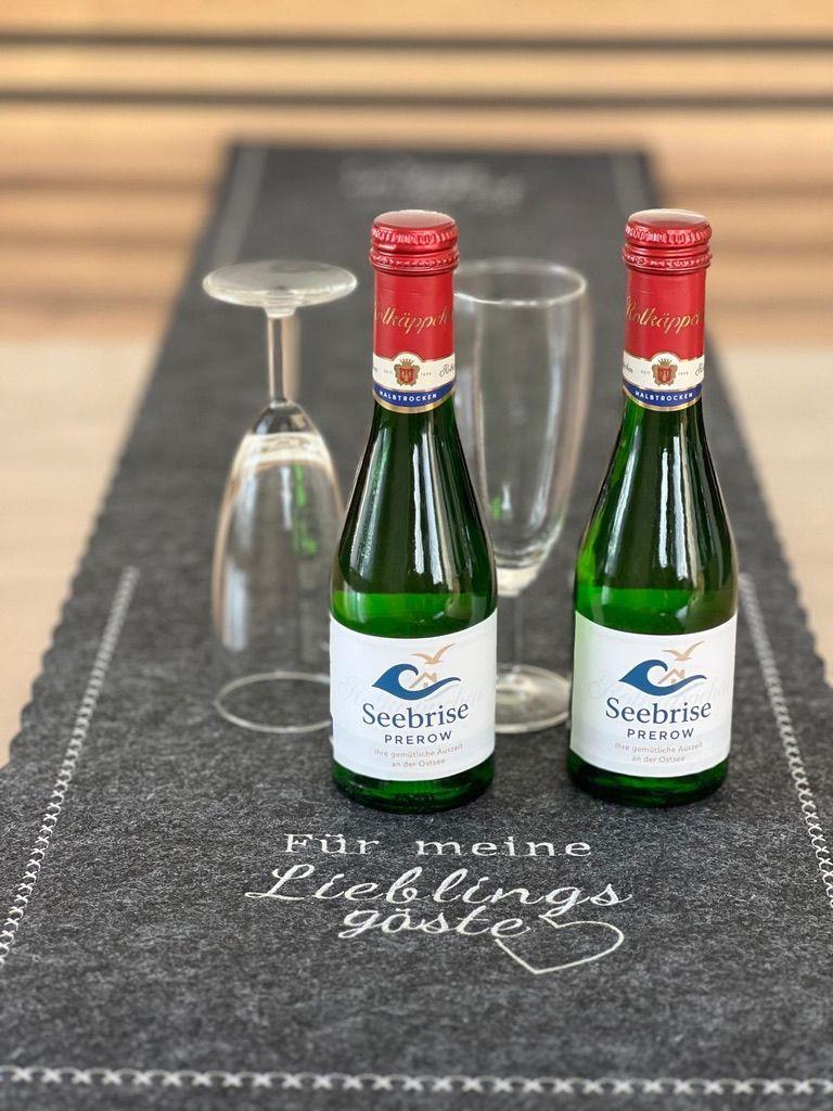 Zwei Seebriese-Flaschen und Gläser auf einem Tisch mit Aufschrift für Gäste.