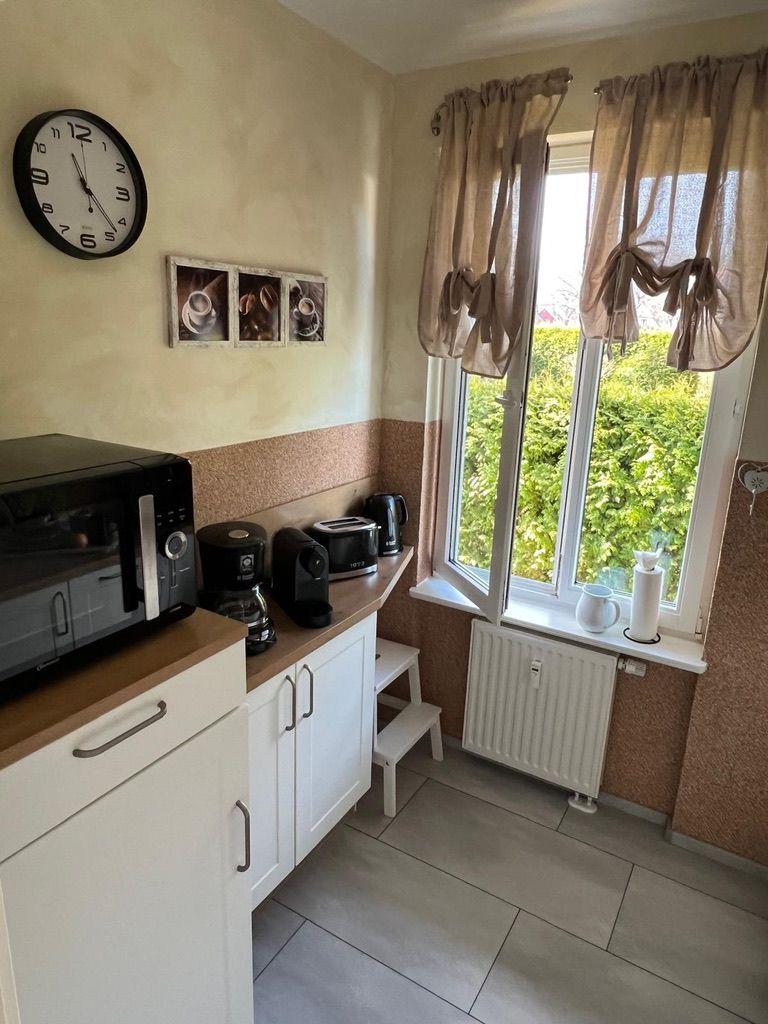 Küche mit Mikrowelle, Kaffeemaschine und Fenster mit Blick auf Grün.