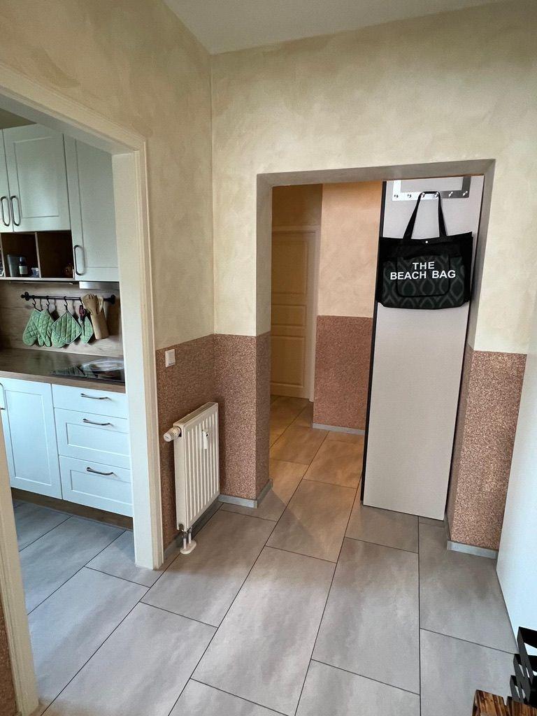 Flur mit Küchenbereich und Garderobe mit Strandtasche.