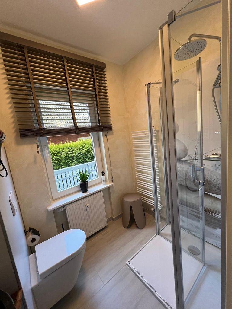 Bad mit Dusche, Toilette und Fenster mit Jalousie.