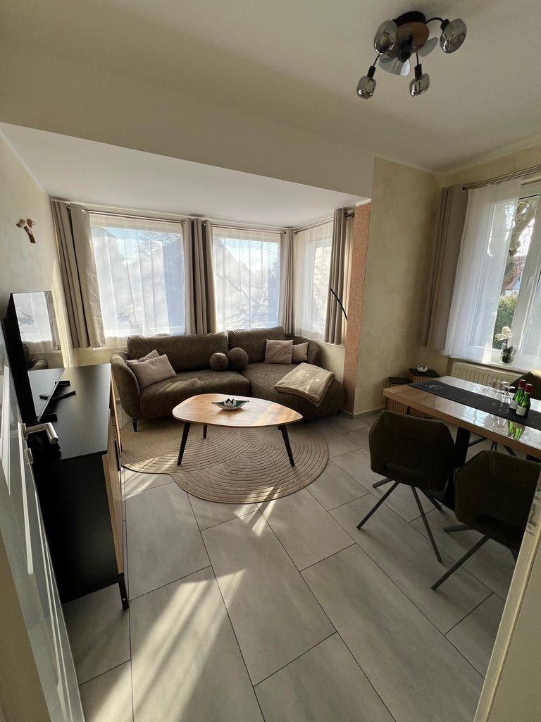 Wohn- und Essbereich mit Sofa, Esstisch und Fenstern.