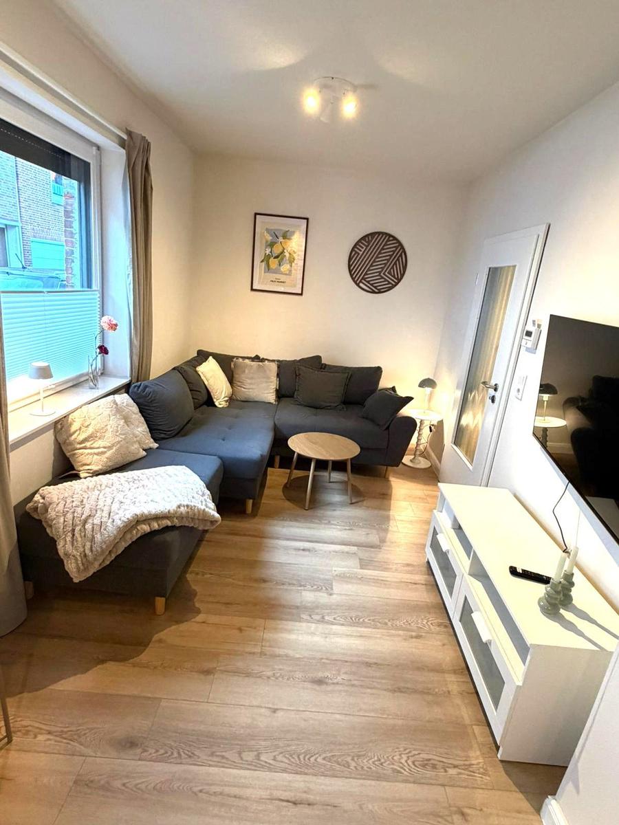 Wohnzimmer mit Ecksofa, Holzboden und Fernseher