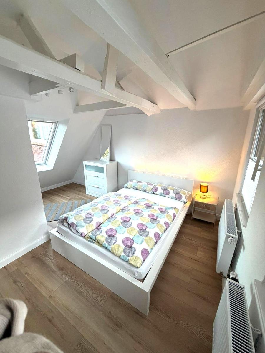 Schlafzimmer mit Dachschräge, Bett, Nachttisch und Fenster