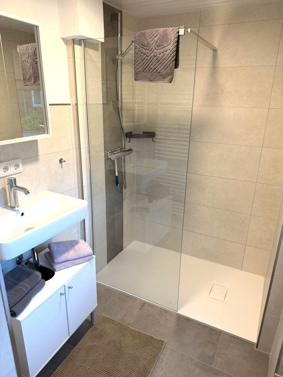Bad mit Dusche, Waschbecken und Handtüchern.