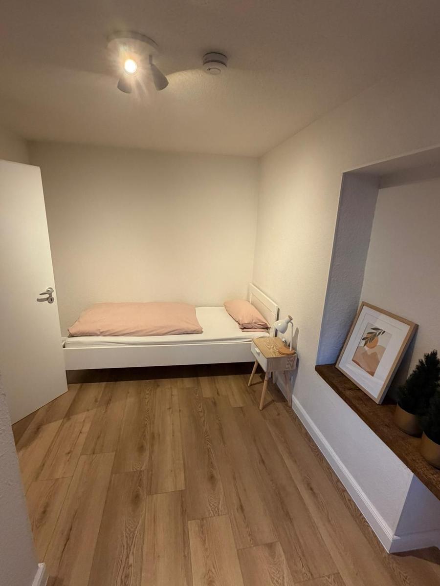 Schlafzimmer mit Bett, Nachttisch und Holzboden.