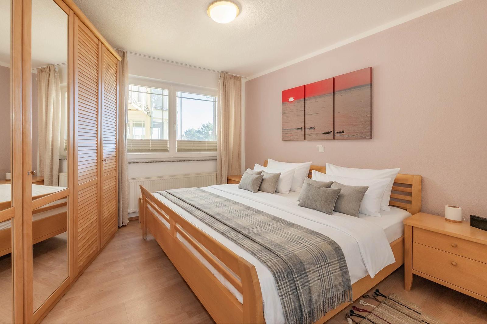 Schlafzimmer mit Holzbett, Kleiderschrank und Fenster mit Blick.