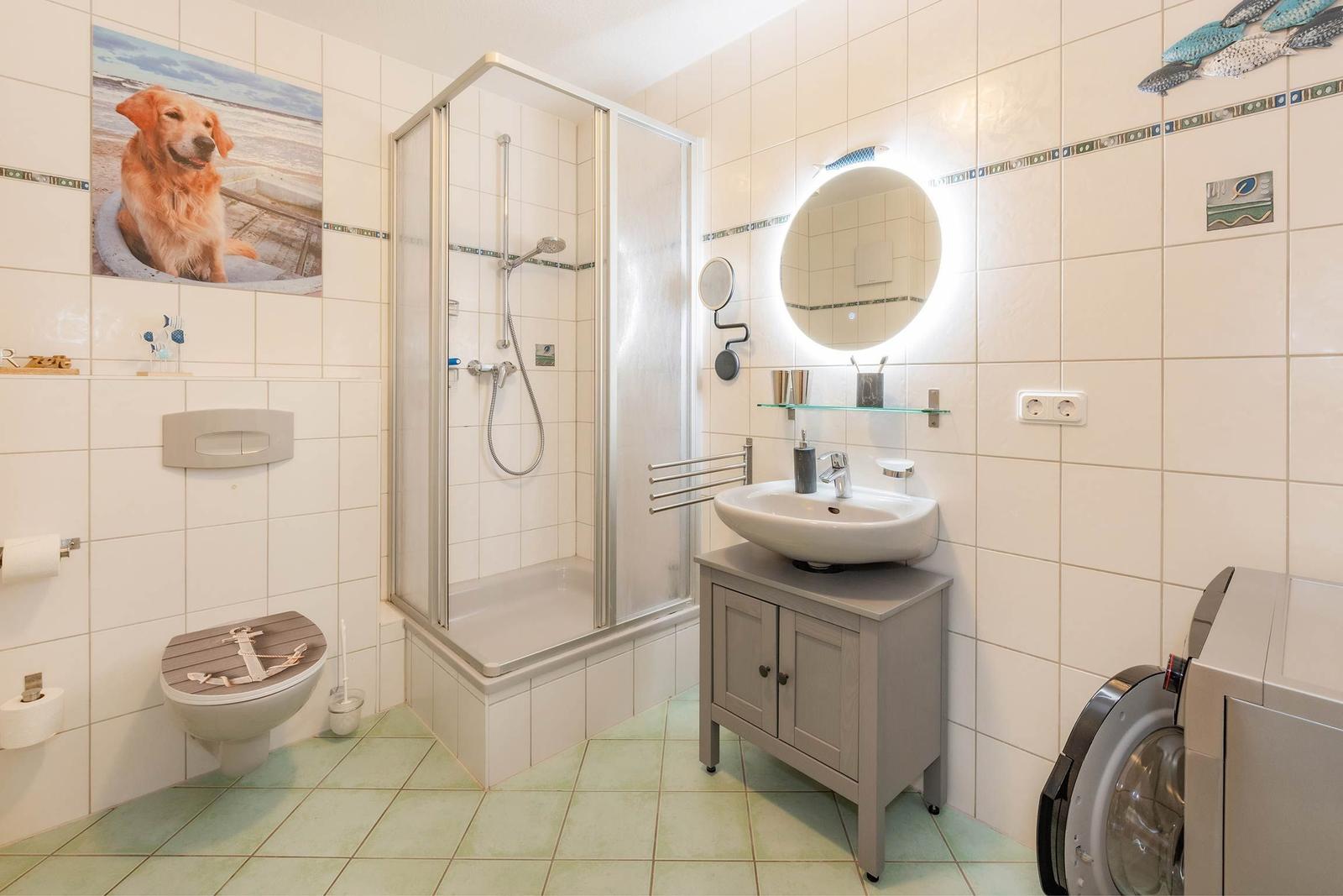 Badezimmer mit Dusche, Waschbecken und Waschmaschine.