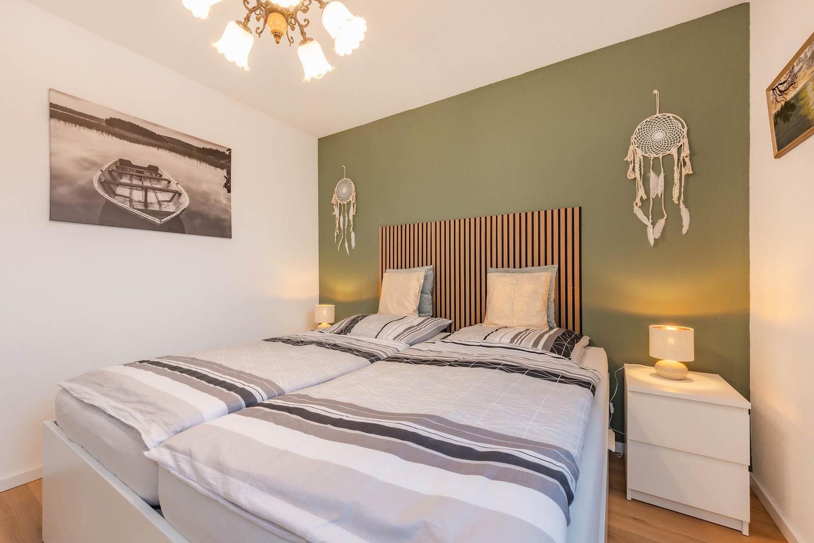 Schlafzimmer mit Doppelbett, grüner Wand und Nachttischen