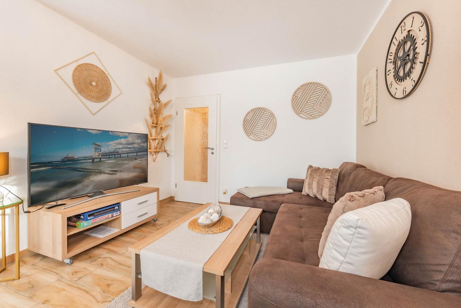 Wohnzimmer mit Sofa, TV und Dekoration an den Wänden.