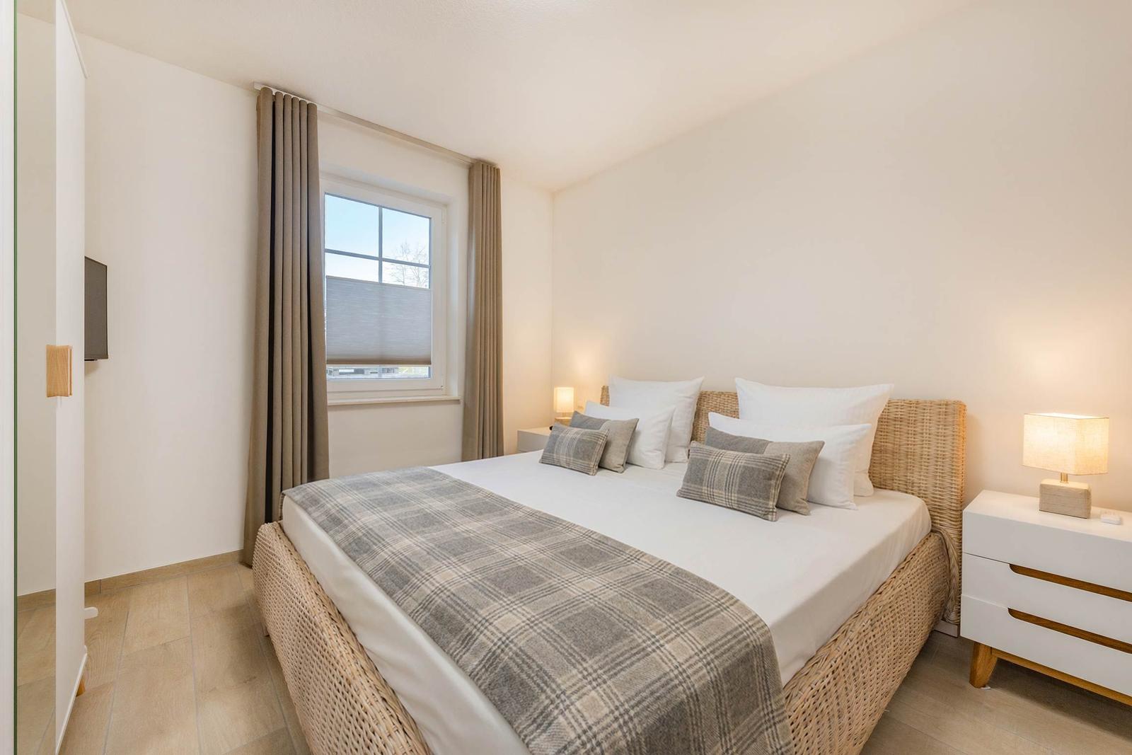 Schlafzimmer mit Bett, Nachttischen und Fenster