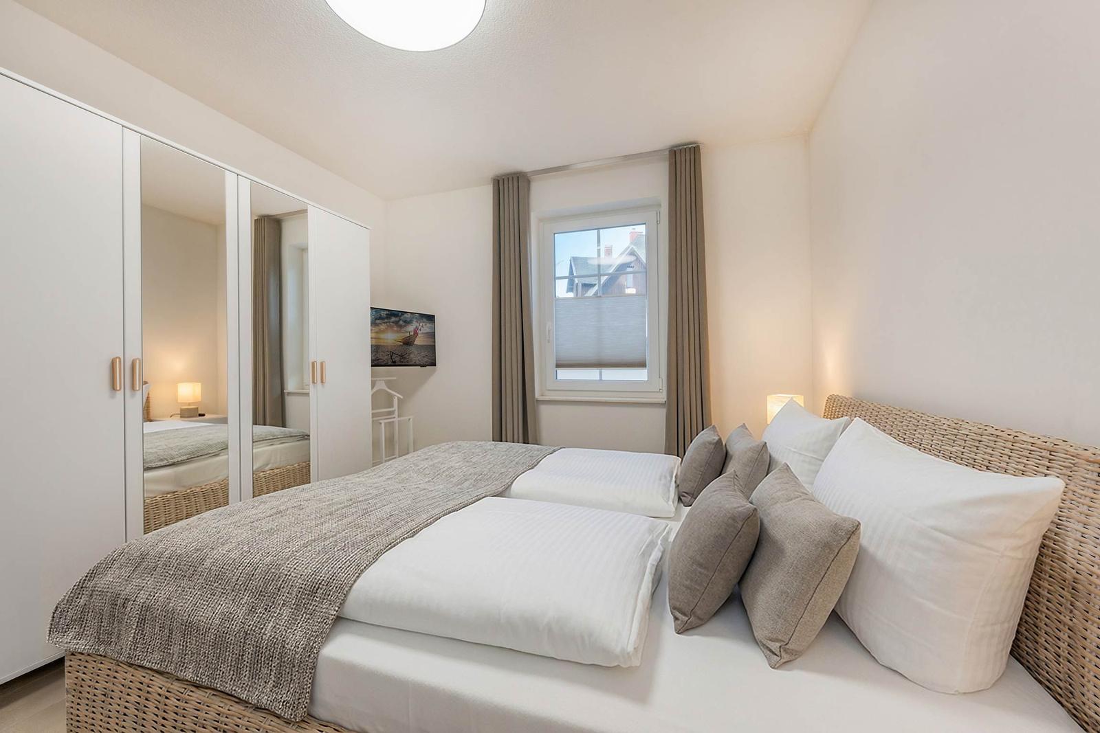 Schlafzimmer mit Bett, Kleiderschrank und Fenster.