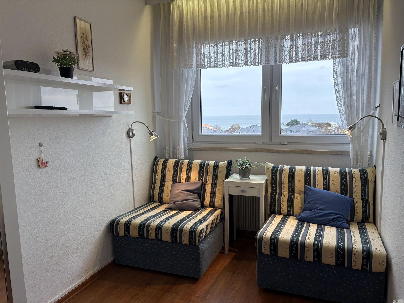 Zwei Sessel mit Streifenbezug stehen vor einem Fenster mit Meerblick.