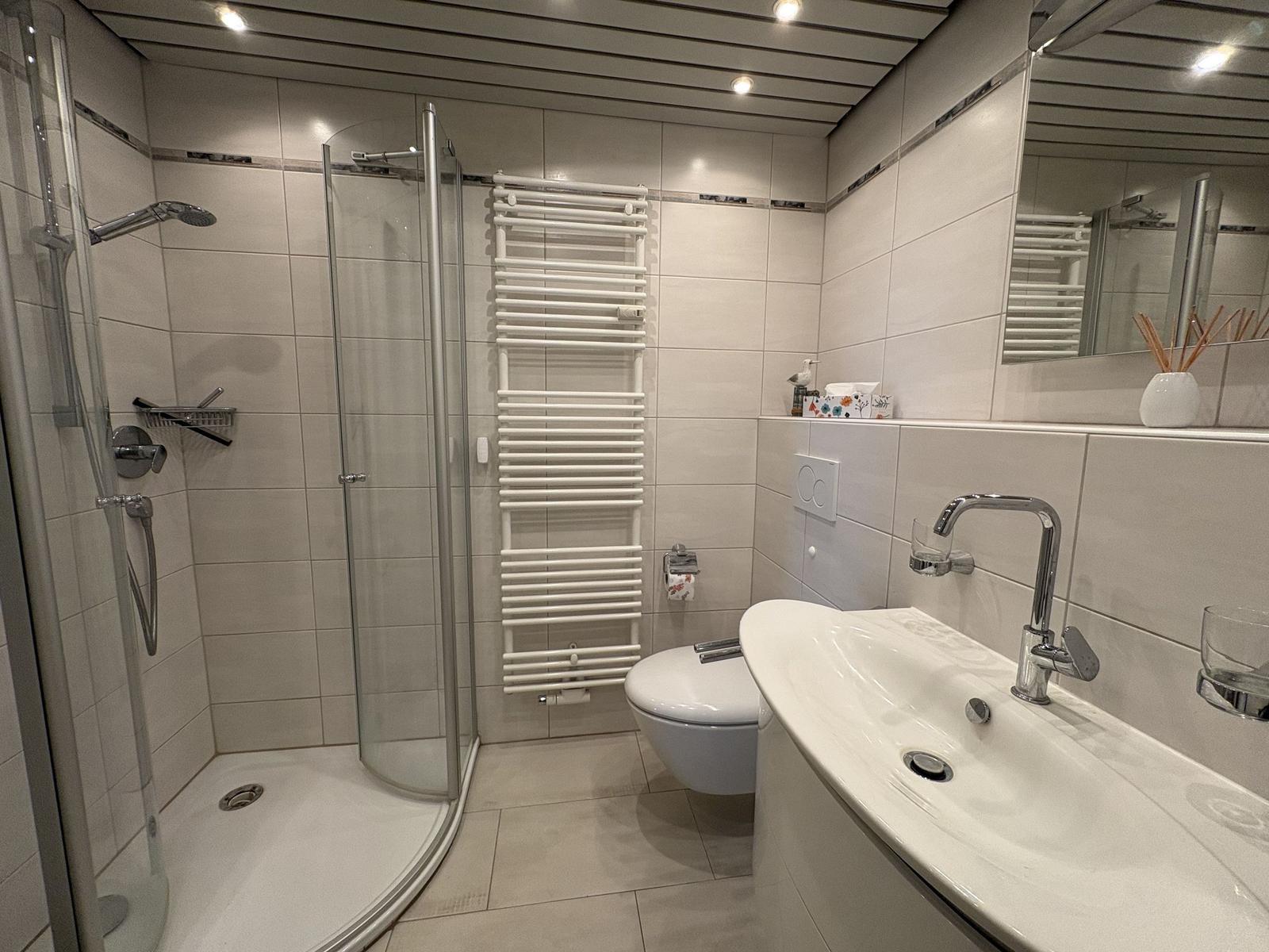 Badezimmer mit Dusche, Toilette und Waschbecken.