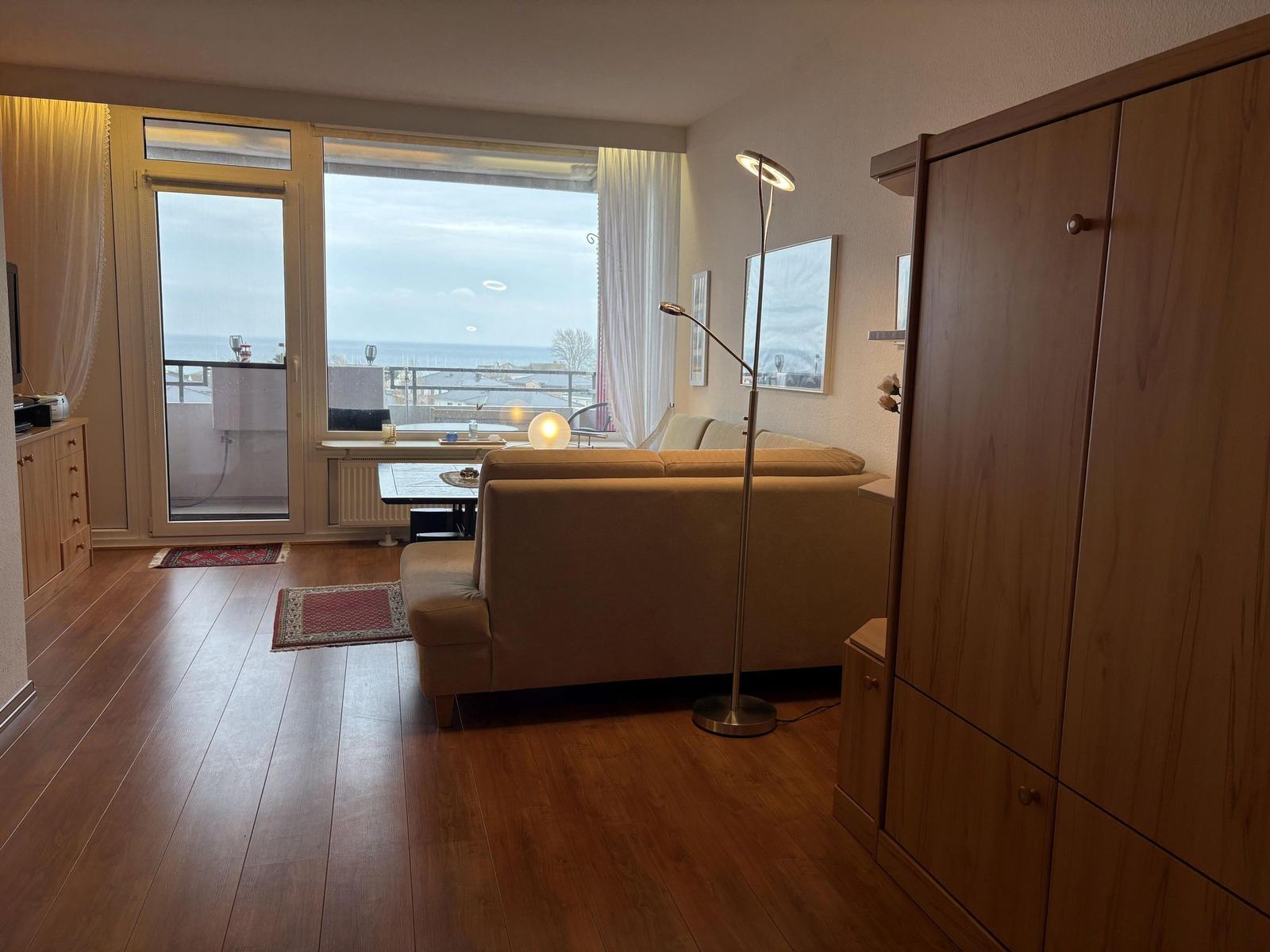 Wohnzimmer mit Sofa, Bodenbelag und Balkon mit Meerblick.