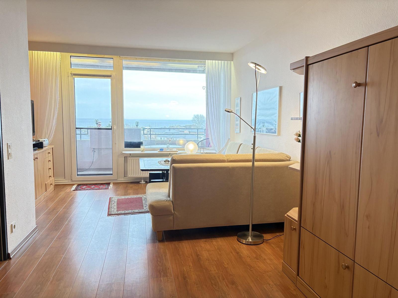 Wohnzimmer mit Sofa, Holzboden und Meerblick über Balkon