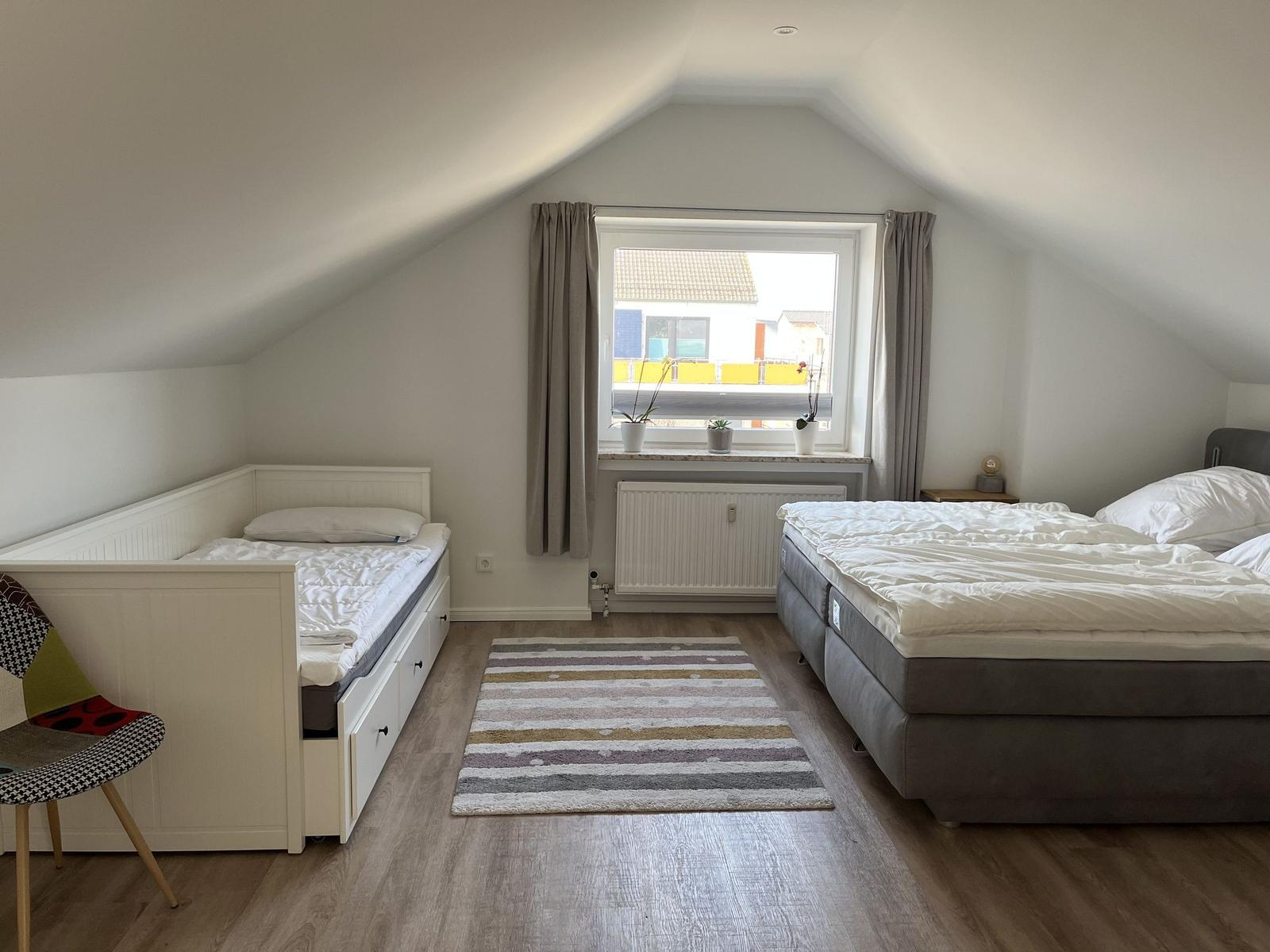 Schlafzimmer mit Doppelbett, Einzelbett und Fenster mit Blick.