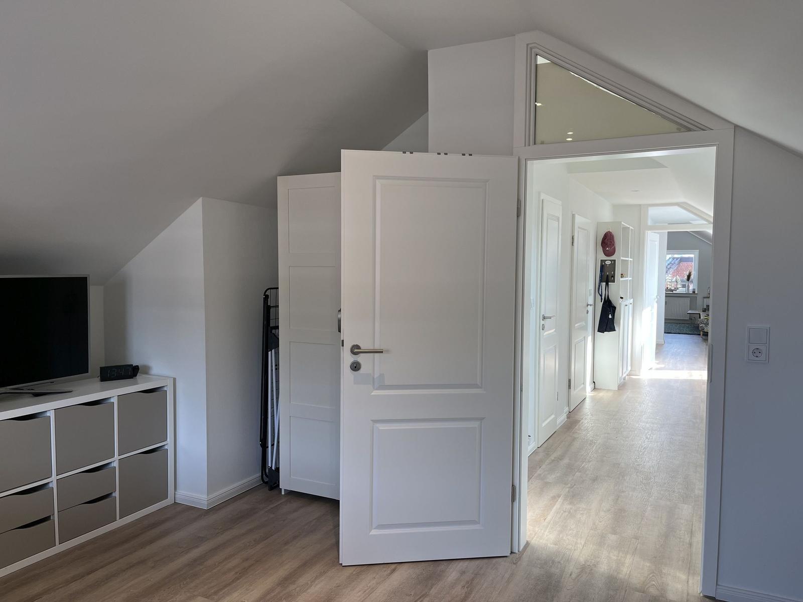 Schlafzimmer mit Fernseher und Tür zum Flur