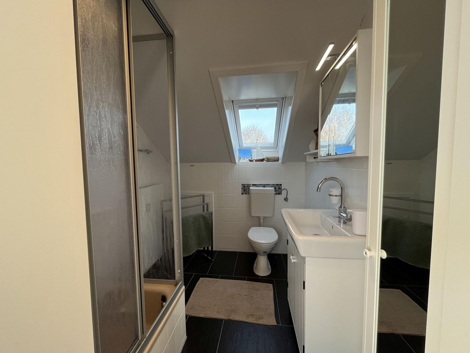 Badezimmer mit Dusche, Toilette und Waschbecken unter Dachschrägen