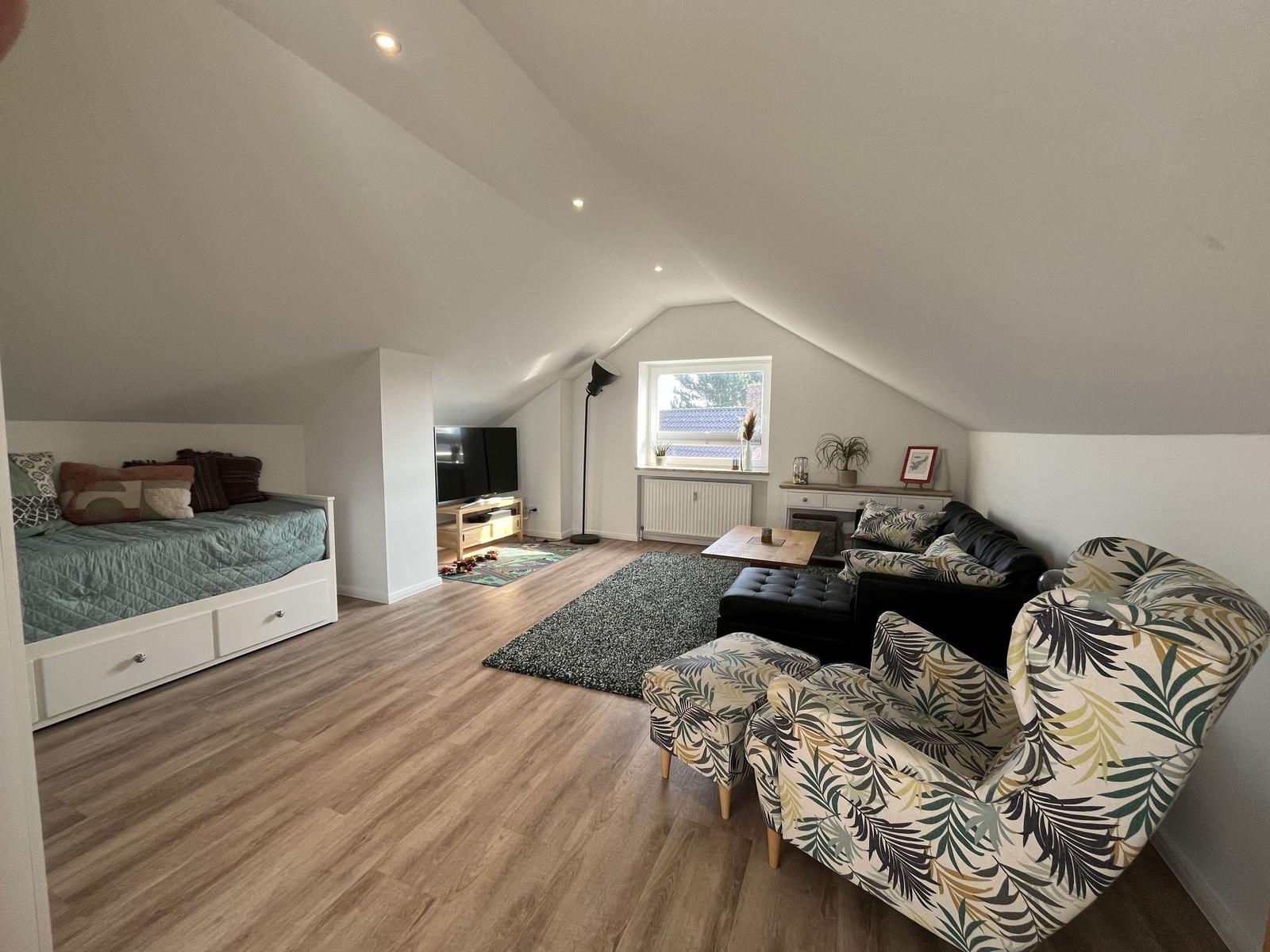 Schlafzimmer mit Bett und Wohnbereich mit Sofa und Sessel.