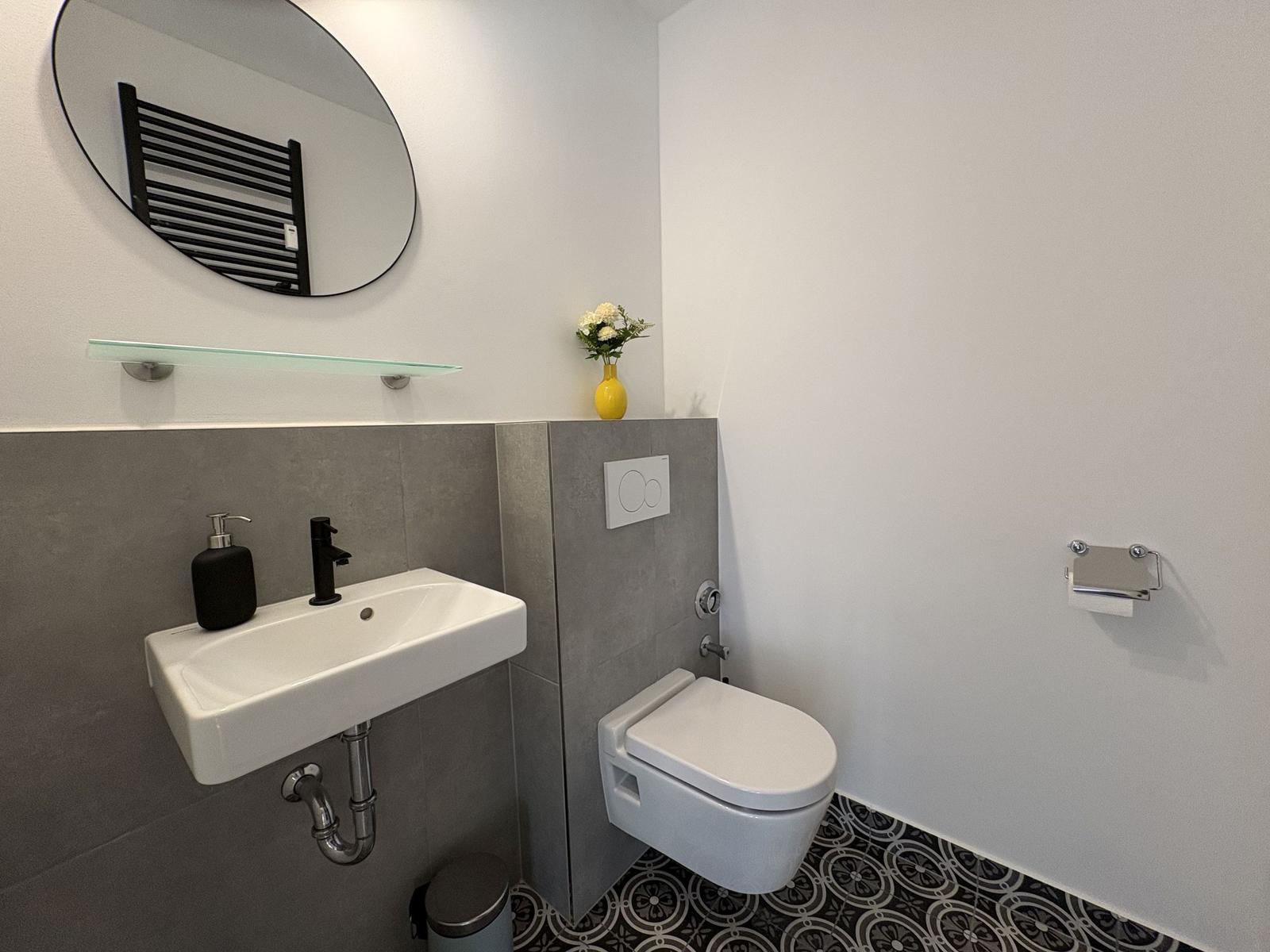 Badezimmer mit Waschbecken, Toilette und Spiegel