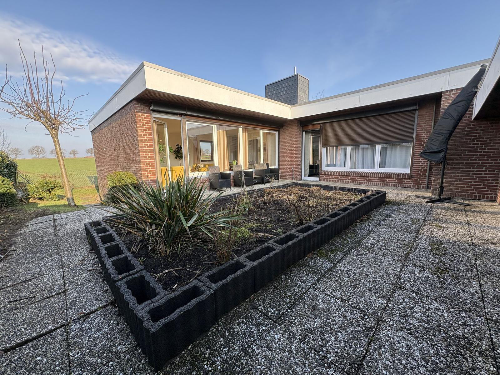 Moderne Villa mit Terrasse und Gartenbereich. Blick in Wohnbereich mit Sitzgruppe.