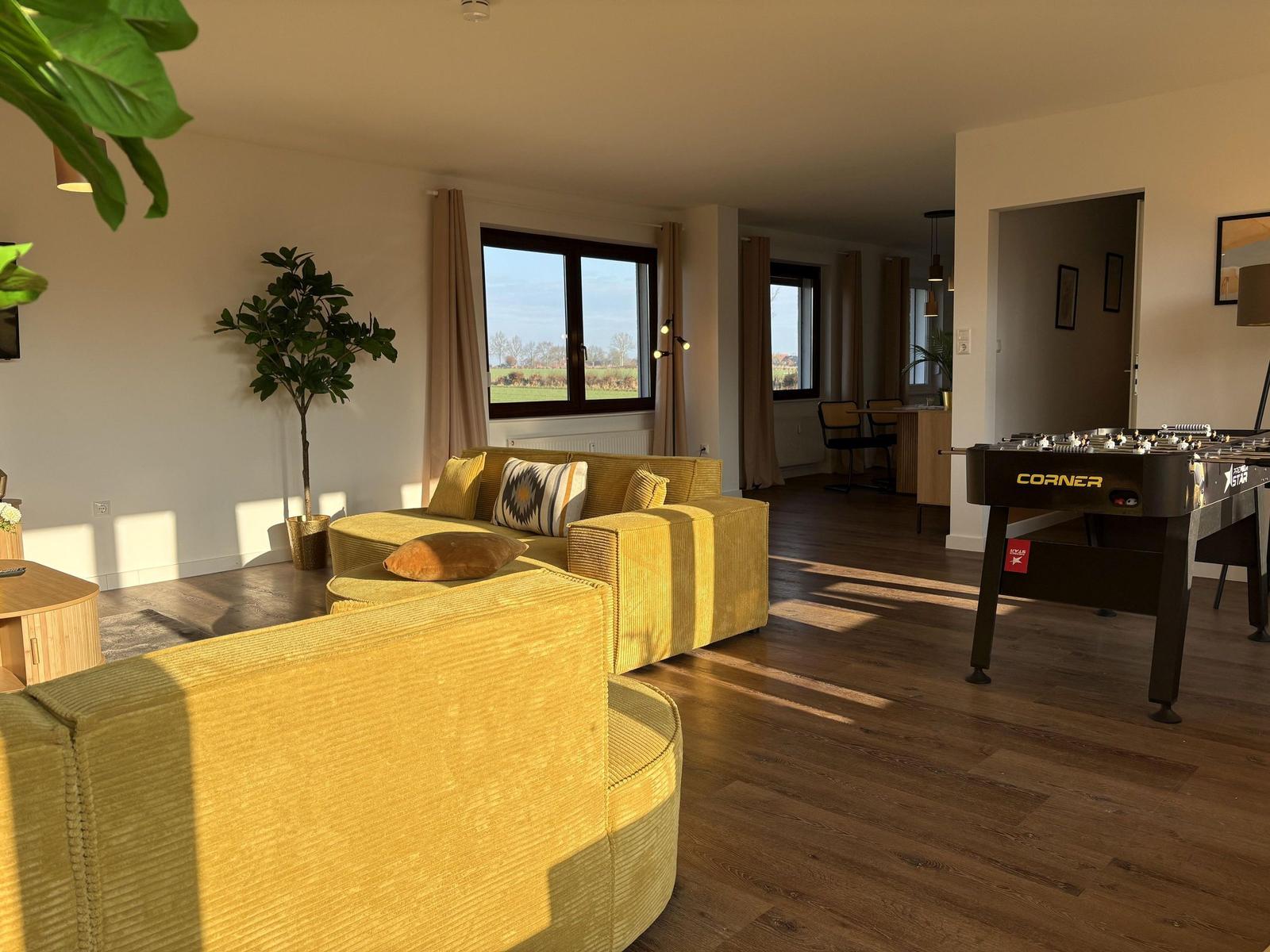 Wohnbereich mit gelbem Sofa, Fußboden und Fenster mit Blick auf Feld.