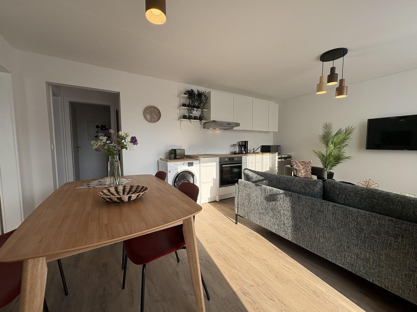 Wohnung mit Essbereich, Küche und Sofa. Holzboden und moderne Beleuchtung.