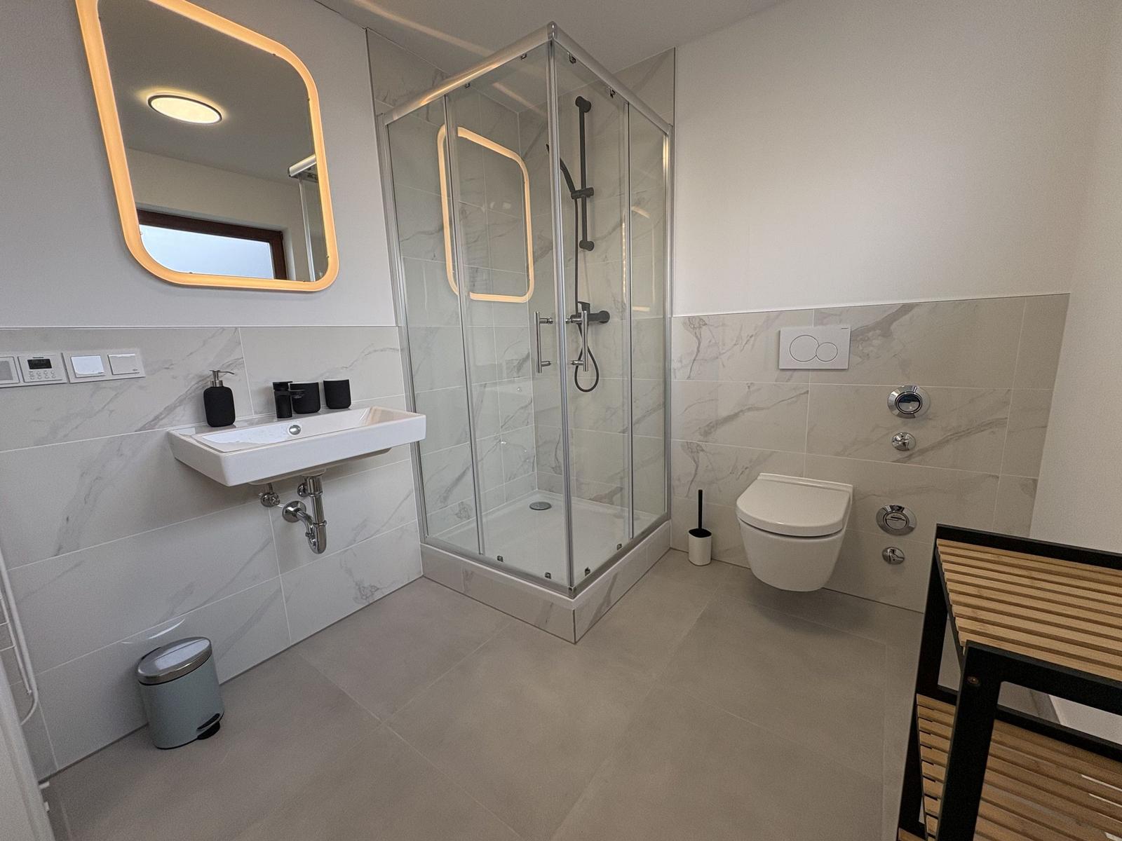 Badezimmer mit Dusche, Waschbecken und Toilette.