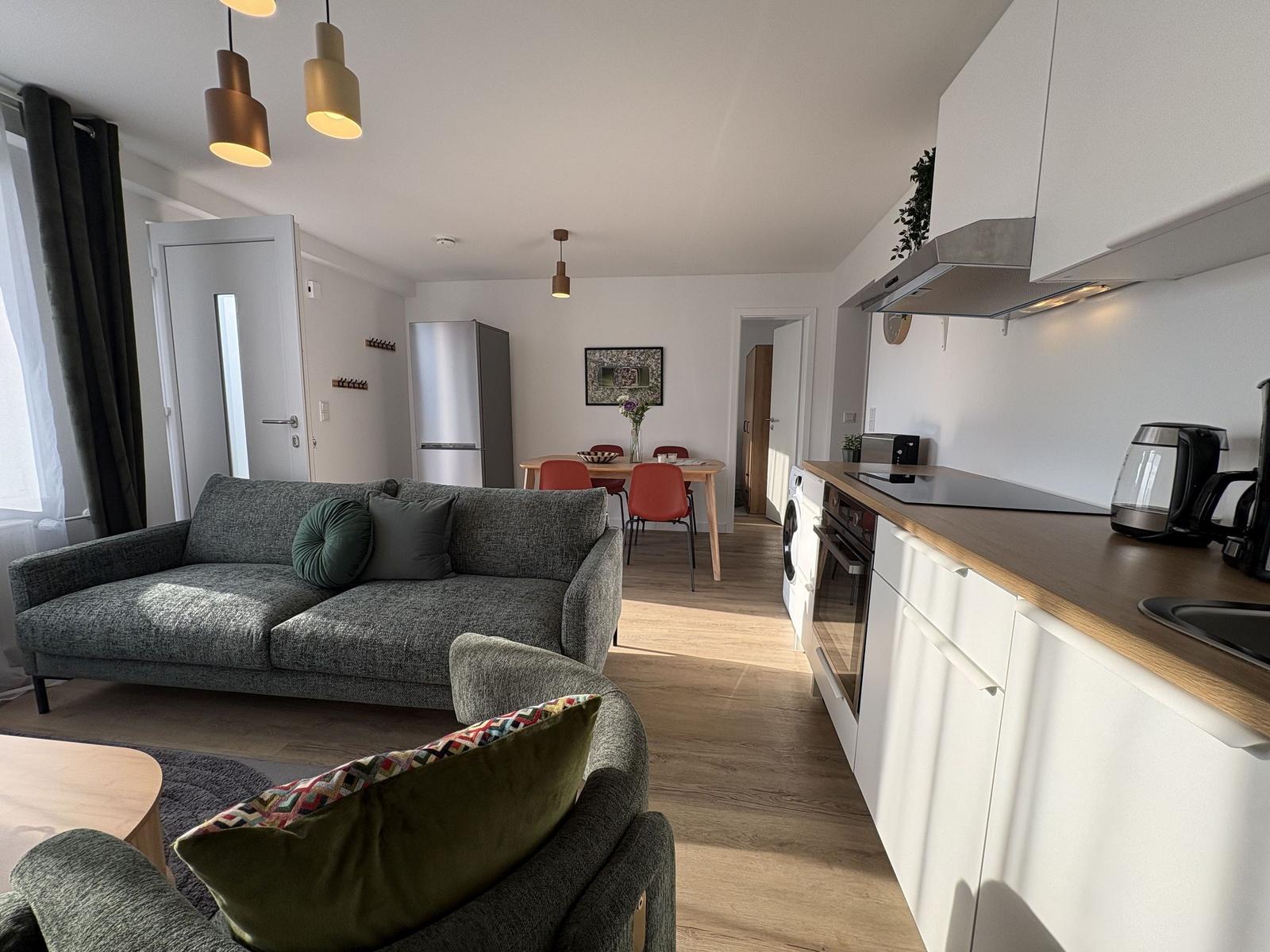 Wohnung mit Küche, Essbereich und Wohnzimmer mit Sofa und Stühlen.