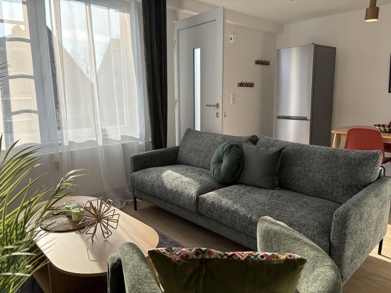 Wohnzimmer mit Sofa, Couchtisch und Küchenbereich im Hintergrund.