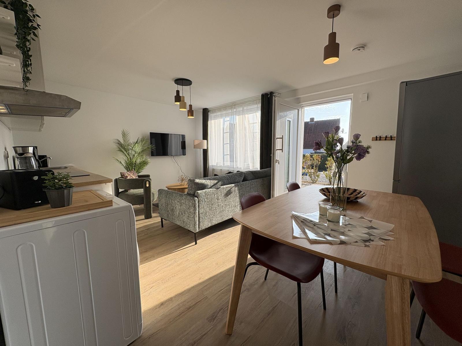 Wohnbereich mit Esstisch, Sofa und Küchenzeile. Durchgang zur Terrasse mit Blick.