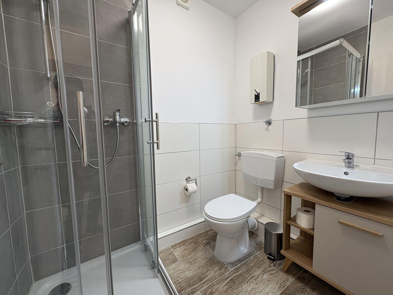 Badezimmer mit Dusche, Toilette und Waschbecken.