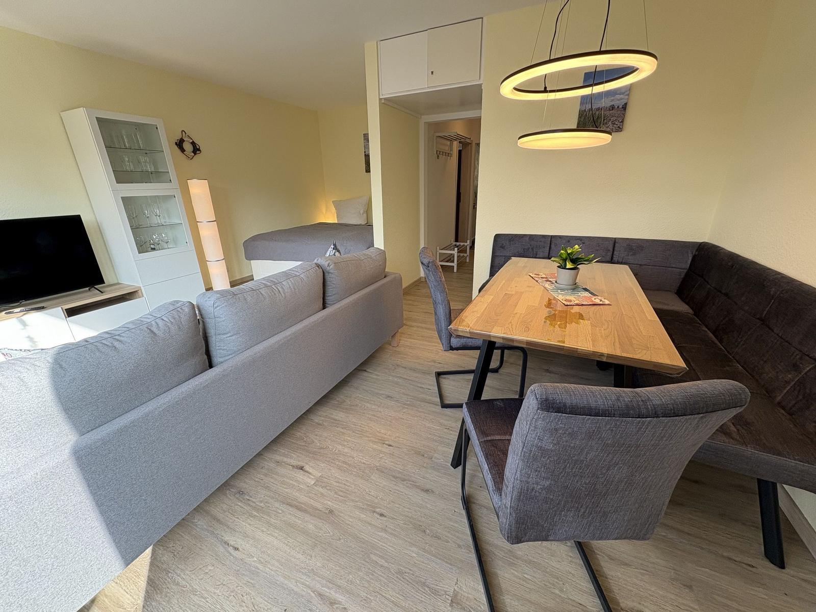 Wohn- und Essbereich mit Sofa, Esstisch und moderner Beleuchtung.