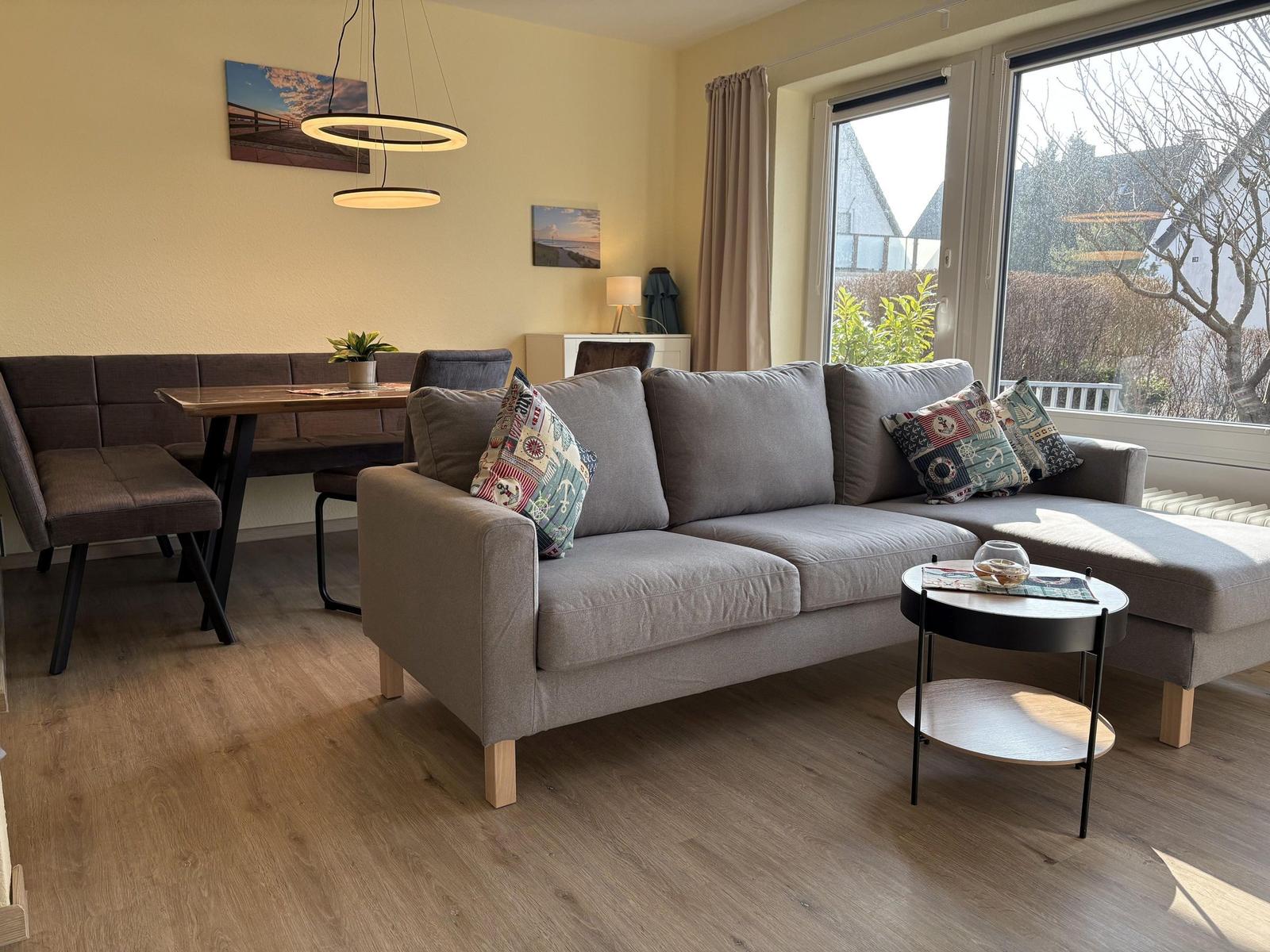 Wohnzimmer mit Sofa, Esstisch und Fensterblick