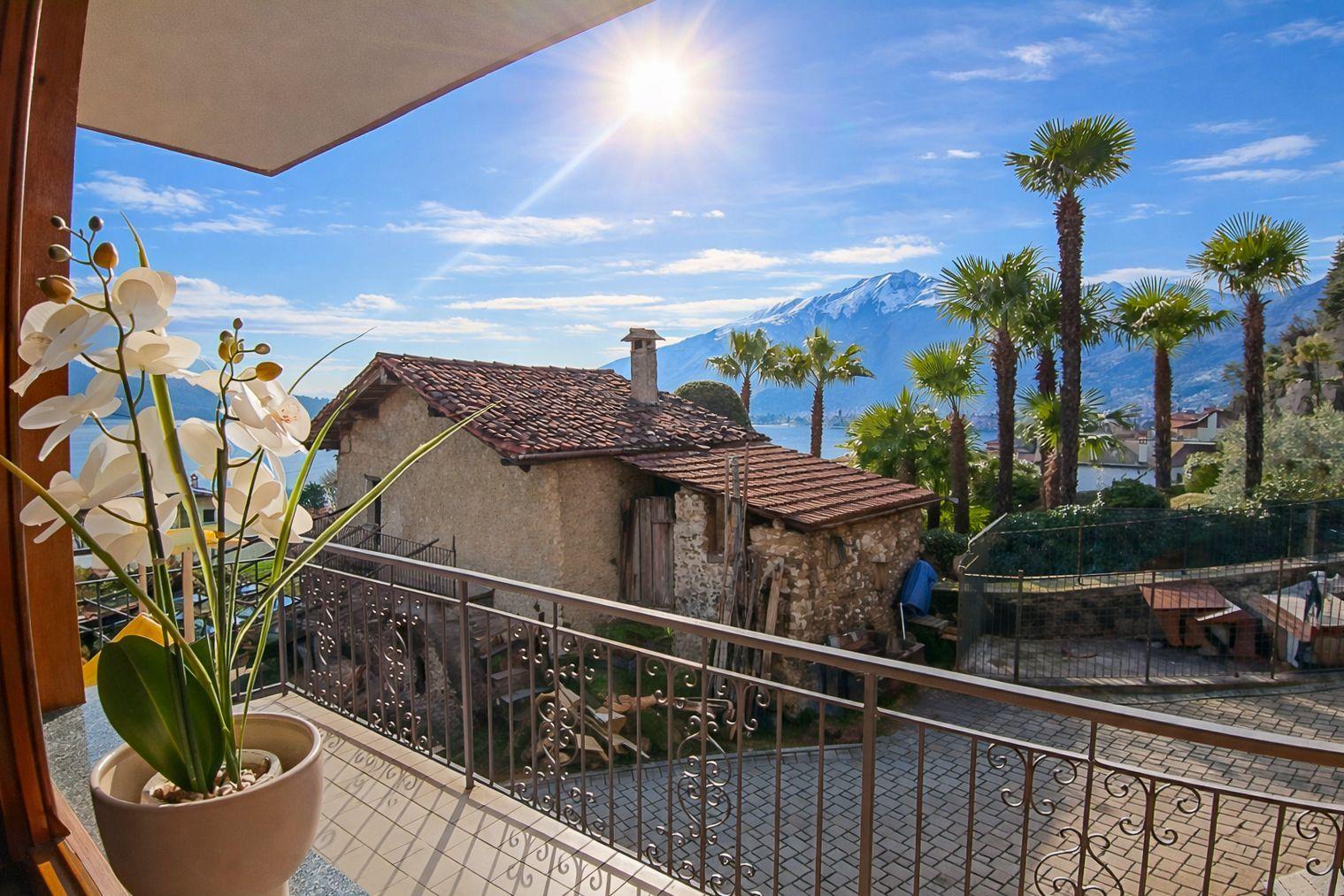 Balkon mit Blick auf Palmen und Berge unter blauem Himmel.