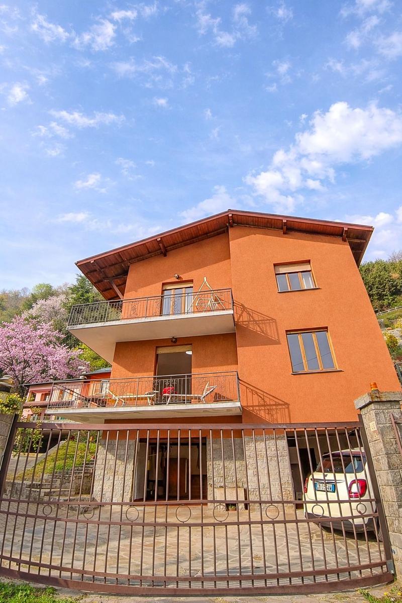 Orangefarbener zweistöckiger Wohnbau mit Balkonen und Gartenzaun.