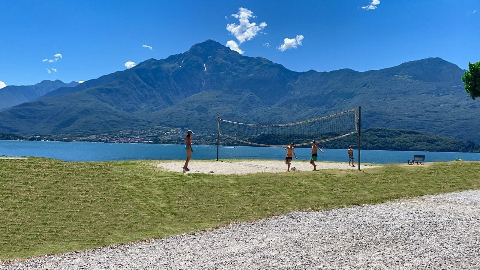 Volleyballplatz am See mit Bergen im Hintergrund.