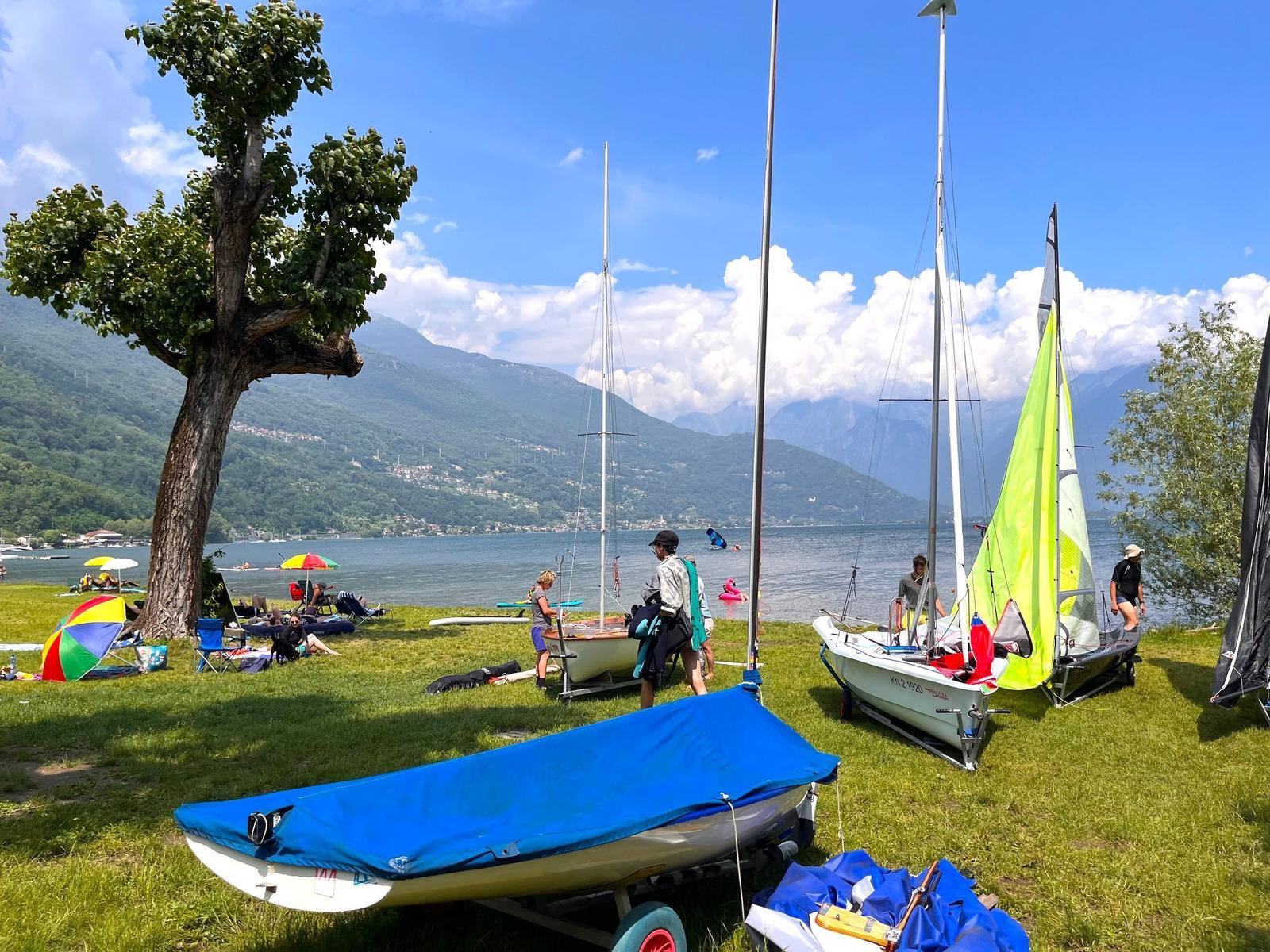 Grünes Ufer mit Booten und Menschen am See