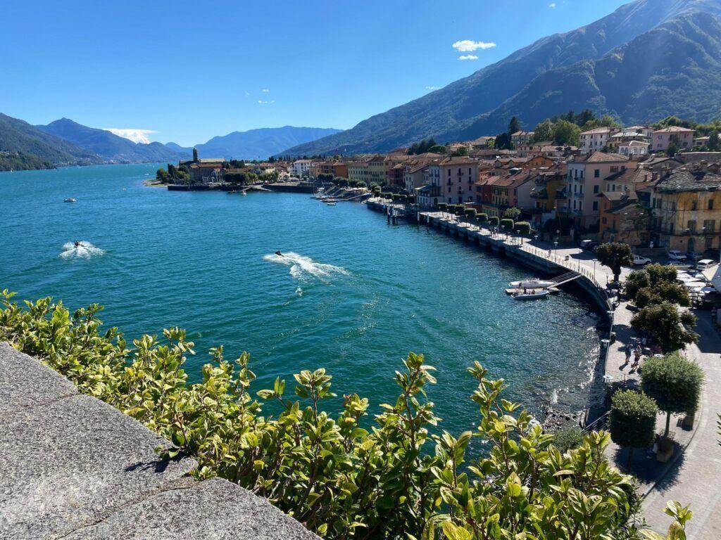 Blick auf einen See mit Booten und einem Dorf an der Küste.