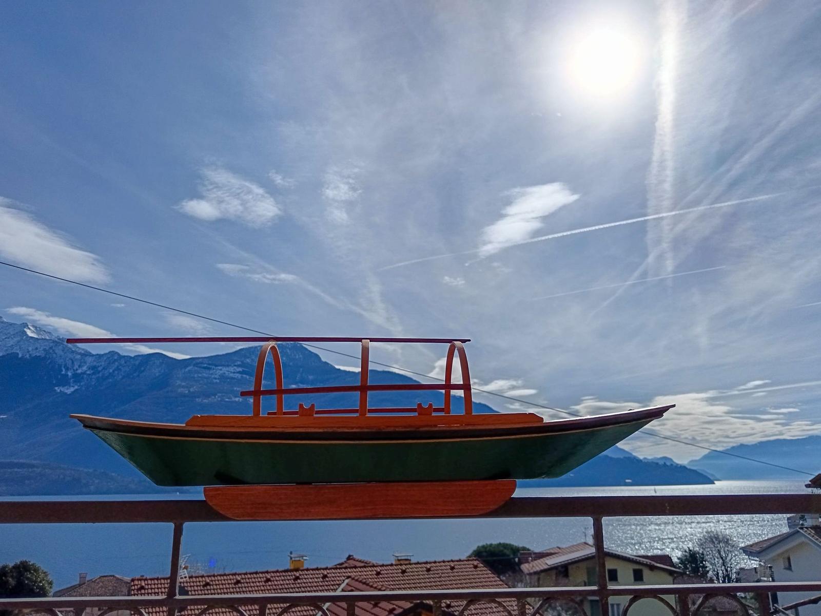 Holzbootmodell auf Balkon mit Berg- und Seeblick.