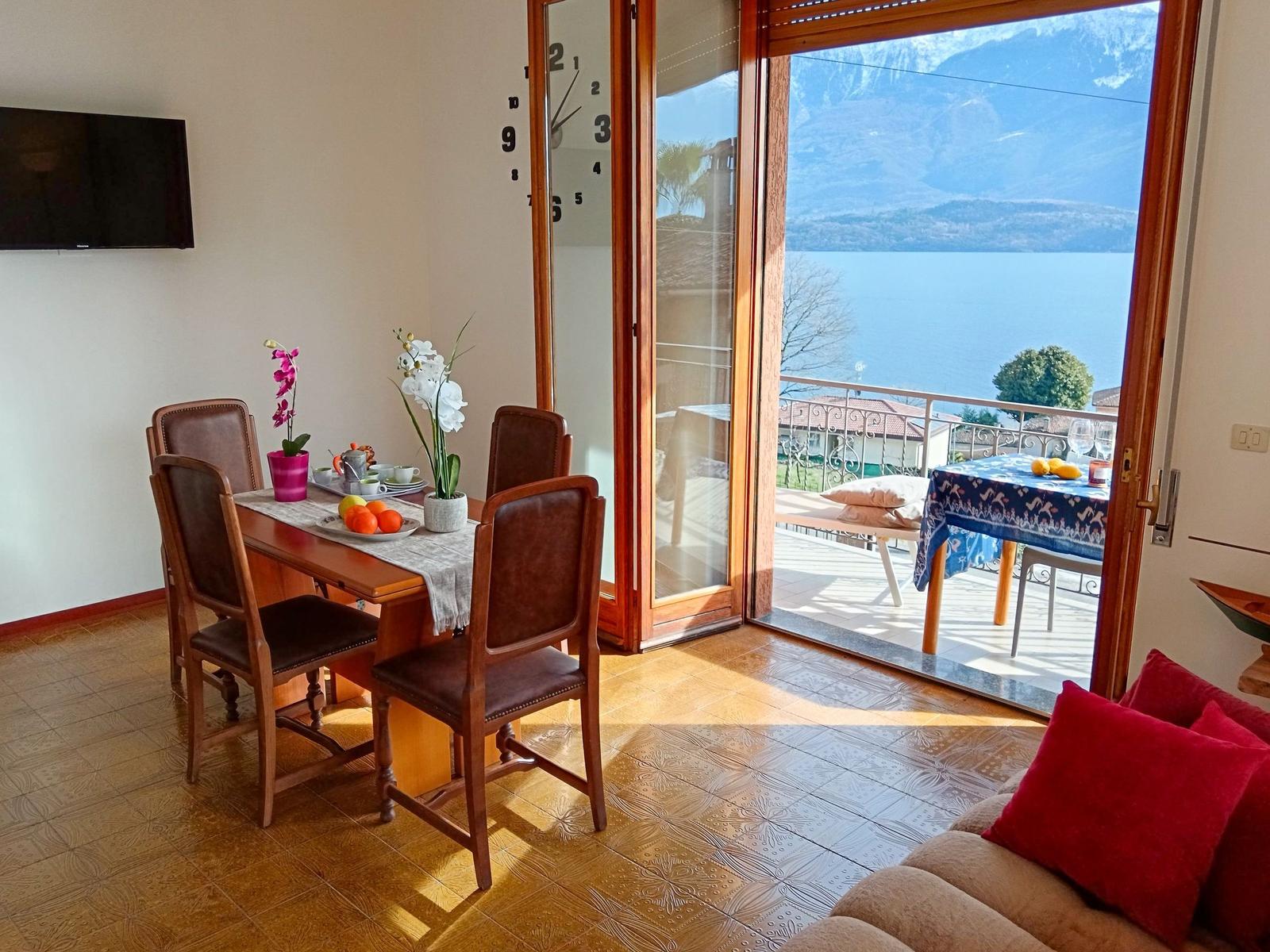 Esszimmer mit Blick auf See und Berge. Terrasse mit Tisch und Stühlen.