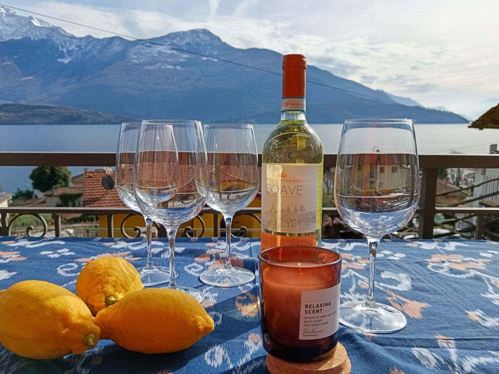 Tisch mit Wein, Gläsern und Zitronen auf Balkon mit Bergblick