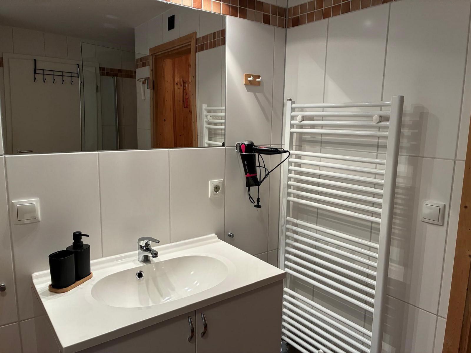 Badezimmer mit Waschbecken, Spiegel und Heizkörper