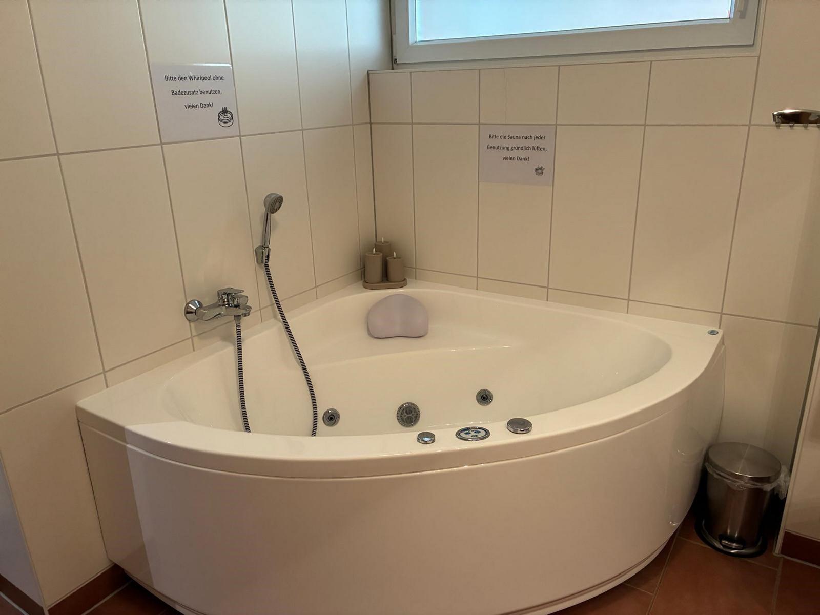 Eckwhirlpool mit Dusche und Kerzen. Anweisungen an den Wänden.