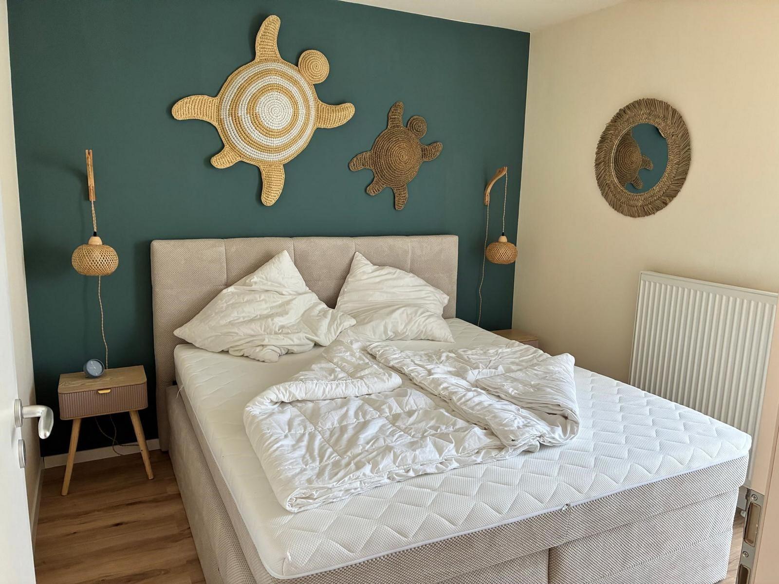 Schlafzimmer mit Bett, Nachttisch und Wanddekoration.