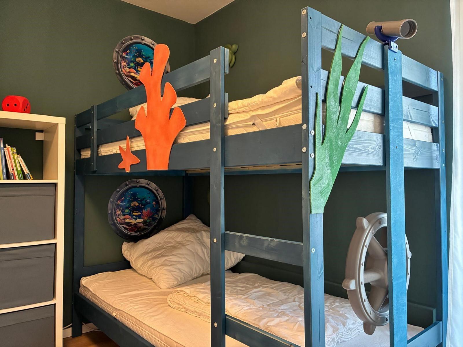 Kinderzimmer mit Doppelstockbett im Schiffsthema mit Korallen und Ruder.