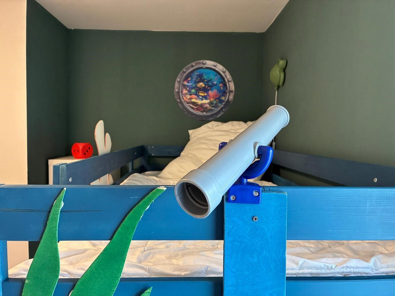 Ein Kinderzimmer mit blauem Bett, Seekopfposter und Fernglas an der Matratze.